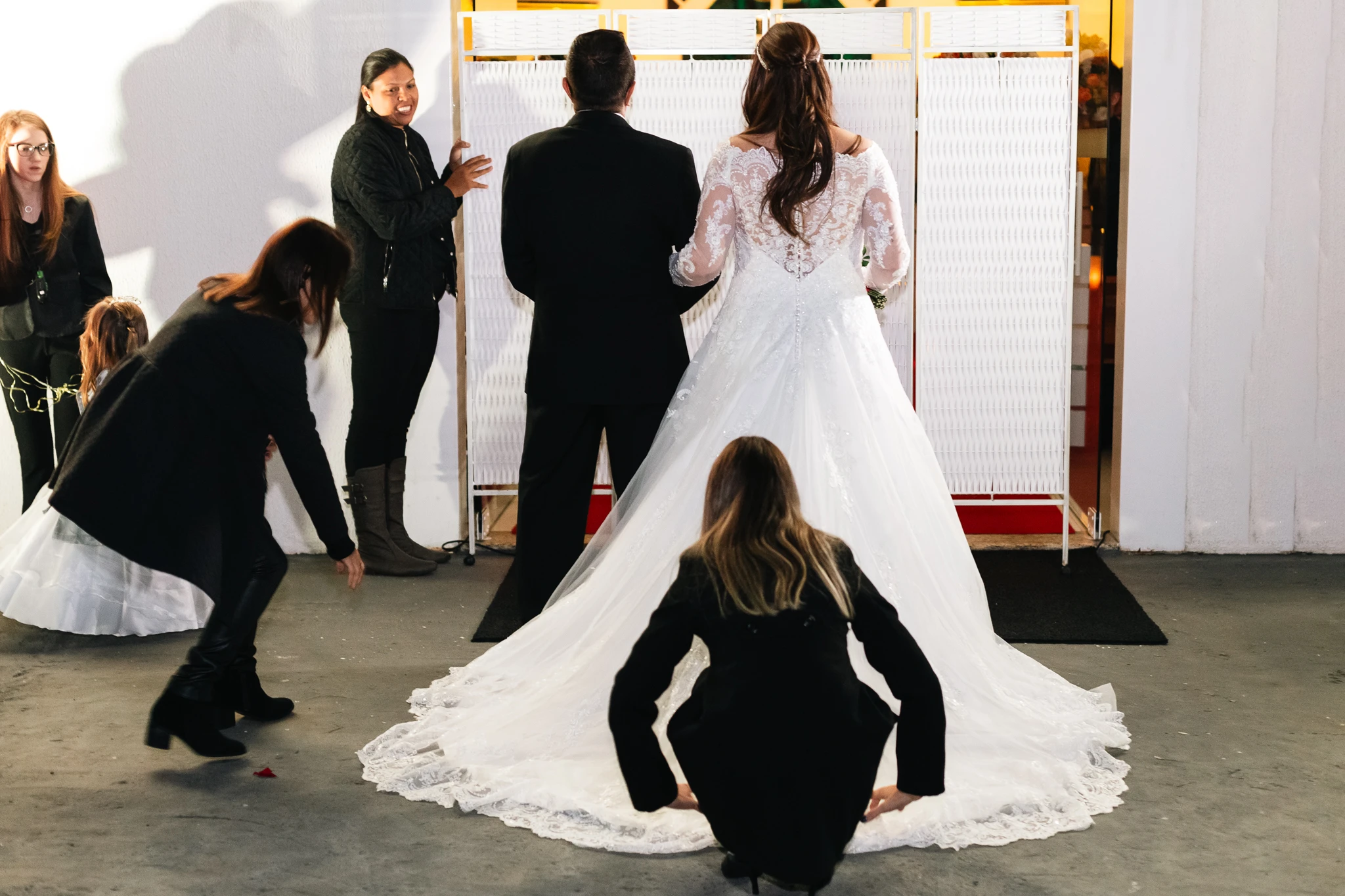 A cerimonialista ajeitando a cauda do vestido antes da entrada
